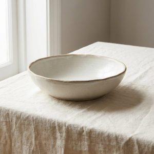 A wide white stoneware serving bowl with a raw clay rim