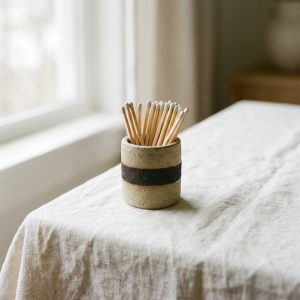 A sand-glazed ceramic match holder with long wooden matches