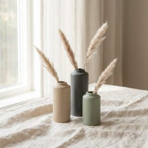 Three small ceramic bud vases in sage, sand and charcoal with dried grass stems
