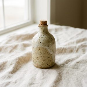 A speckled stoneware oil pourer with a cork stopper
