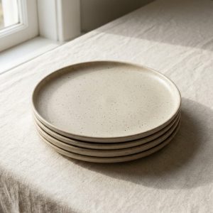 A stack of four oatmeal stoneware dinner plates