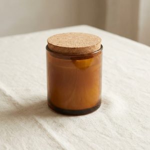 An amber glass jar of candle refill wax with a cork lid
